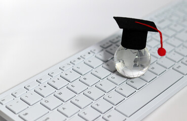 A globe with an academic cap on a keyboard. Educational Diversification Concept.
