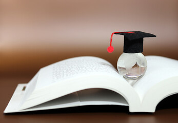 A transparent globe with a bachelor's cap on an open book. Global business learning.
