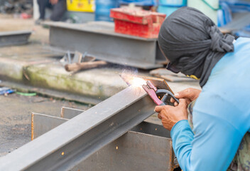 Worker welder without personal protective equipment welding base beam suport.