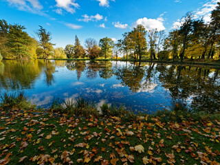 Autumn in the park in Silherovice, Czech Republic, next to the palace that once belonged to the Rothschild family. A pond with visible reflections of trees in autumn colors