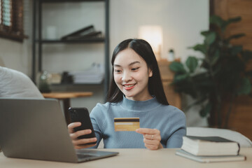 doing online shopping on the sofa in the living room, Use a credit card to make online payments while at home on day off, Use a laptop to enter a credit card information to pay for the service.