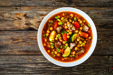 Fresh vegetable soup with meat, chickpeas and lentil on wooden table
