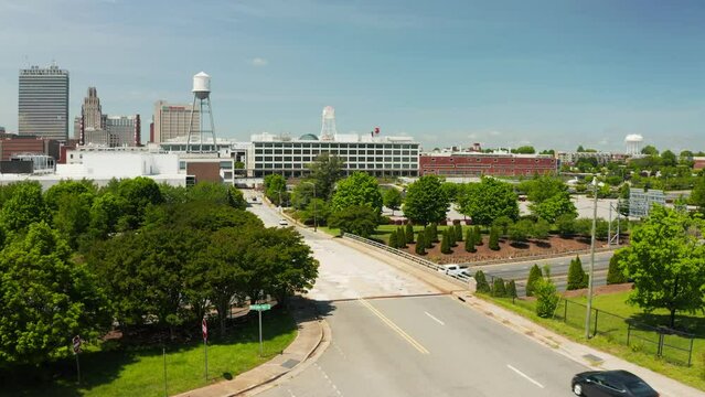A rising drone shot of the Winston-Salem skyline in North Carolina in the summer over the freeway.