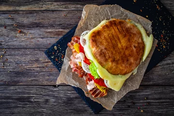 Foto op Canvas Big sandwich with grilled chicken breast and cheese and fresh vegetables on wooden table  © Jacek Chabraszewski