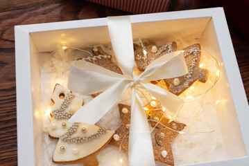 Christmas gift boxes with homemade cookies and lights of garland on wooden background