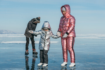 The sport family is skating on the ice of Lake Baikal. Winter Siberian landscape