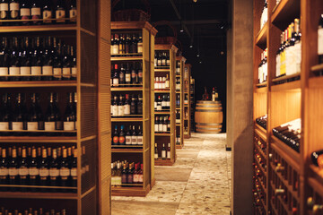 Long corridor with wooden shelves fulled bottles of elite wine in cellar of alcohol store.
