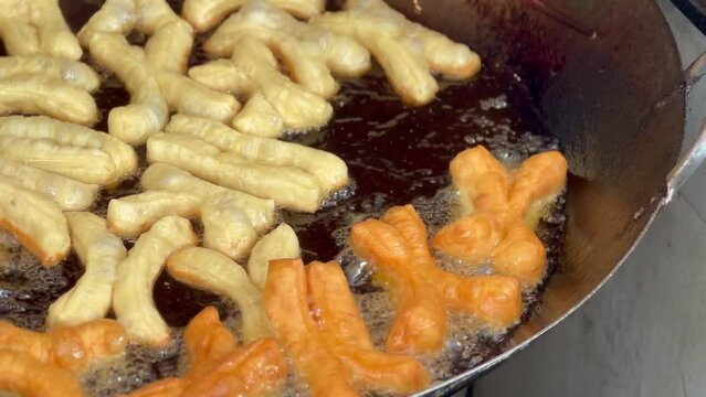 4K deep-fried dough stick or patongko being fried in a pan with boiling oil, Thailand street food breakfast favorite among tourists