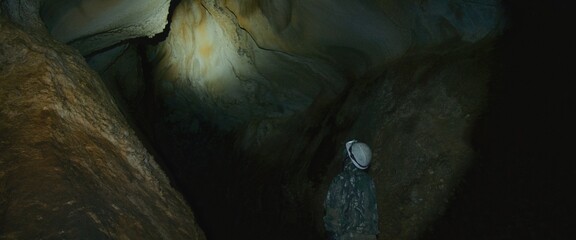 Professional speleology worker in helmet carry out visual inspection on underground nature....