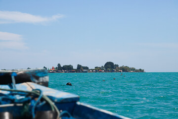 Fototapeta na wymiar An increasingly developed traditional fishing village on an island can be seen from the bow of a fishing boat