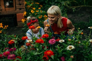 Mom and daughter happily smell flowers in their countryside garden