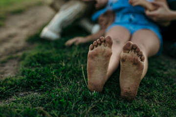 Countryside barefoot kid with dirty feet, enjoying the hug of her family