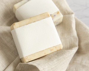 Beige handmade soap bars with blank label on linen towel close up, mockup