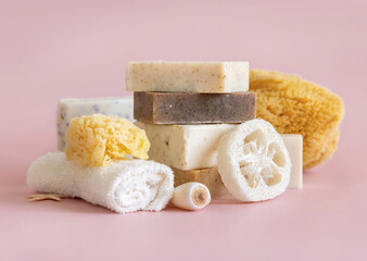 Beige soap bars, seashells, natural sponges and towel on light pink close up