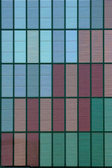 Geschlossene Jalousien an einer Hochhausfassade in verschiedenen, dezenten Farben