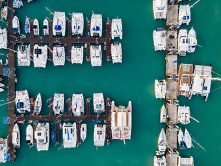 Aerial drone view of Chalong Pier in Phuket, Thailand. Many boats, yachts, sailboats and catamaran moored at the pier platform of Ao Chalong Bay, one of centers to travel around Andaman Sea.