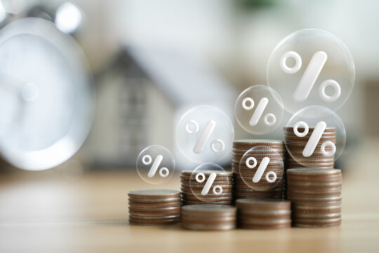 Percentage symbol for interest rate increase on coin pile and sample house. Interest rate hikes, home loans, mortgages, home taxes, investment concepts and asset management.