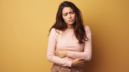 Obraz premium sad young woman holding her stomach, illness, cramps, health, color background, girl suffering, painful periods, stomach-ache, abdominal, griping, bellyache, tummy-ache, gripes, portrait, ill, pastel