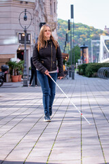 Portrait of blind woman with white cane walking on the street