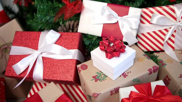 Under a modern Christmas tree, elegantly wrapped gift boxes enhance the holiday ambiance in a home with a white background, alongside holiday Xmas ornaments, as a design element for New Year decor. 
