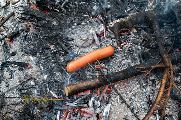 Grilling sausage on skewer over open fire