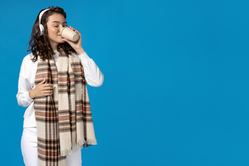 Girl in winter clothes with coffee, on a blue background.