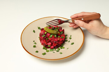 Vinaigrette salad on plate and fork in hand on white background