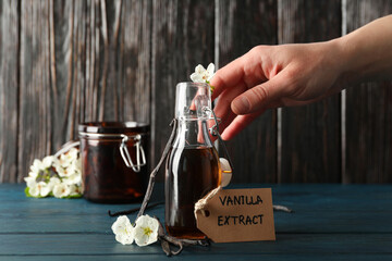 Vanilla extract in a bottle on a wooden table - obrazy, fototapety, plakaty