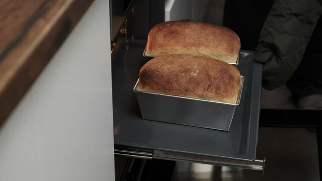 Close-up of a chef's hands taking baked bread out of the oven. the cook bakes bread.