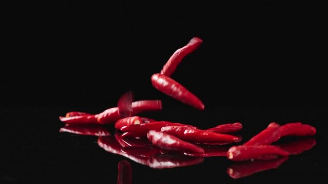 Falling of red chili peppers in slow motion,on a black background. 