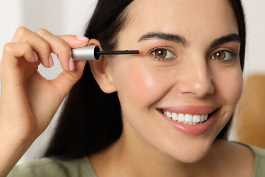 Beautiful woman applying serum onto her eyelashes, closeup. Cosmetic product