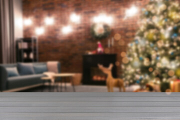 Light grey wooden table against blurred view of room with Christmas tree. Space for design