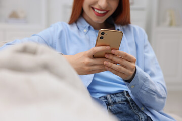 Woman sending message via smartphone indoors, closeup