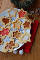 Fototapeta premium Christmas cookies with fake “glass” made of melted candies on plate on wooden table with festive decorations