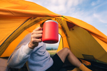 Traveler holding coffee mug in camping tent. Vacation, travel, adventure concept