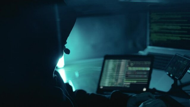 A hacker working on laptop at night. Hacker using computer breaks into government data servers and infects their systems with a virus. Hacker, Cyber security, Cyber crime concept