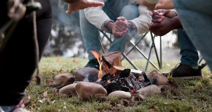 Campfire, friends and warm hands outdoor for fun, adventure and travel in woods. Camping, men group and people together at wood fire or flame on camp site chair for holiday, freedom or nature closeup