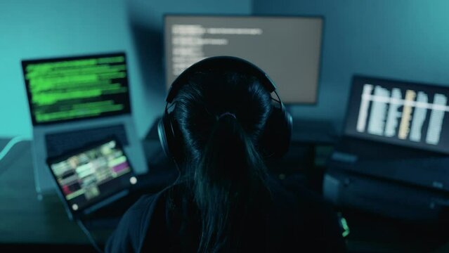 Back view of woman hacker hacking database computer. Young woman developer programmer, software engineer, IT support working hard on computer to check coding in system