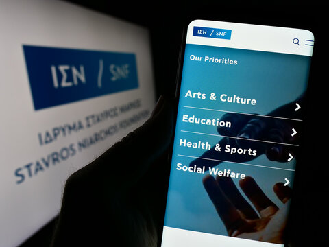 Stuttgart, Germany - 11-03-2023: Person holding cellphone with website of Greek orgsniation Stavros Niarchos Foundation (SNF) in front of logo. Focus on center of phone display.