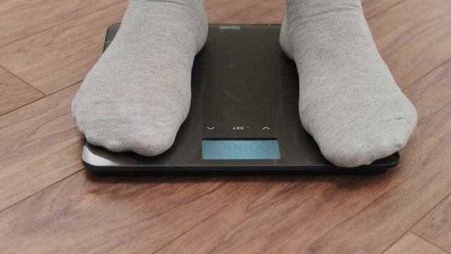 A man steps on a digital scale to control his weight while losing weight. overweight and obesity. healthy lifestyle concepts
