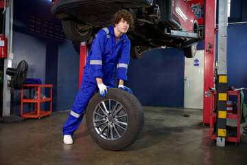 Fototapeta na wymiar mechanic holding and pushing a tire for fixing in garage