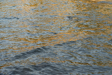abstract water surface with waves and golden reflections in the morning relaxing sea water texture