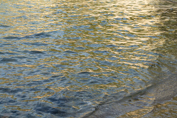 golden reflections of sunlight in sea water on the beach natural rippled water surface for relaxation