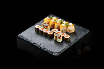 Set of different sushi rolls on a black board. Assorted Japanese sushi with salmon, eel, shrimp