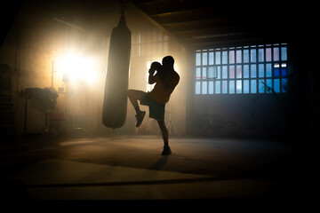 Kickboxing or martial arts fighter hits punching bag with knee in the gym. High quality photo