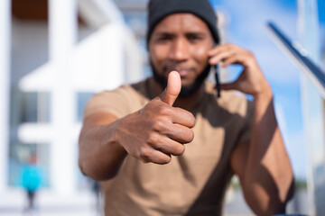 Closeup of a young pensive latin man pointing thumb up. Confident facial expression.