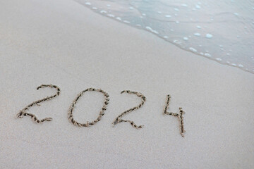 handwritten inscription 2024 on the sand by the sea