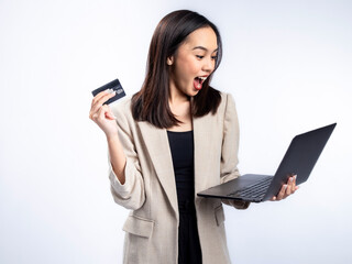 Naklejka premium A portrait of an Indonesian Asian woman wearing a cream-colored blazer, using a laptop, and showing a card. Isolated against a white background.