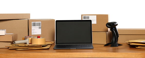 Parcels, laptop and barcode scanner on wooden table against white background. Online store