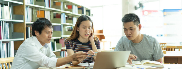 Group of asian students researching for project in library of university.